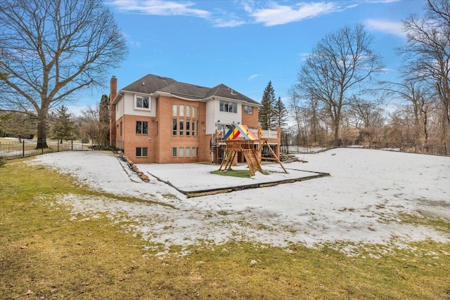 rear view of property featuring a playground, brick siding, fence, a chimney, and a patio area