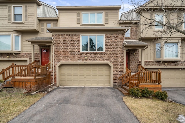 townhome / multi-family property with a garage, aphalt driveway, and brick siding