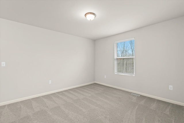 spare room with carpet flooring, visible vents, and baseboards