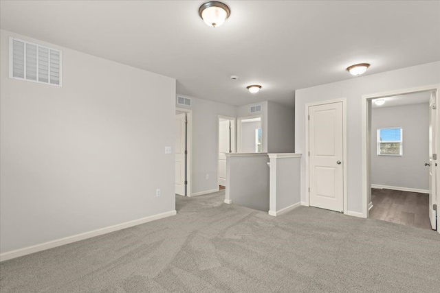 carpeted spare room with visible vents and baseboards