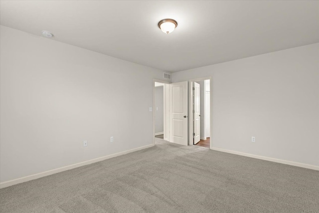 carpeted spare room with visible vents and baseboards