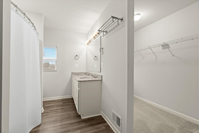 bathroom featuring wood finished floors, vanity, visible vents, and baseboards