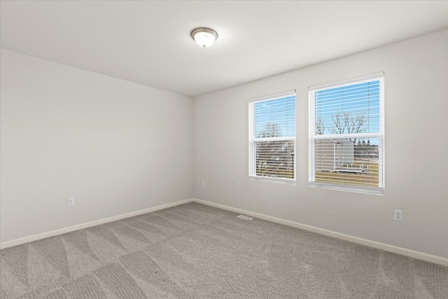 spare room featuring carpet floors, visible vents, and baseboards