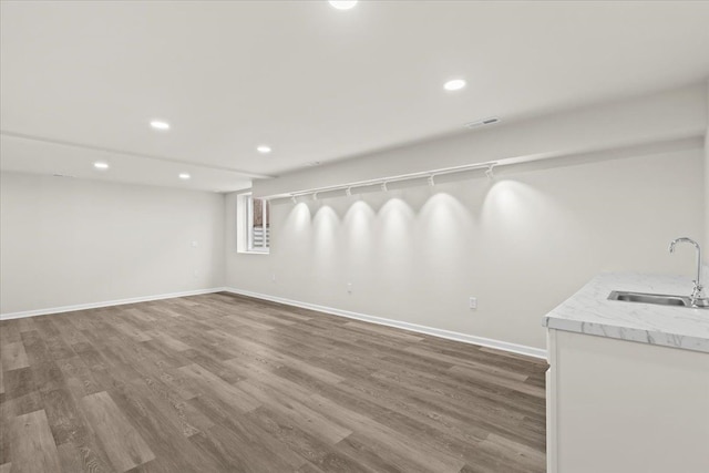 interior space featuring visible vents, baseboards, a sink, and wood finished floors