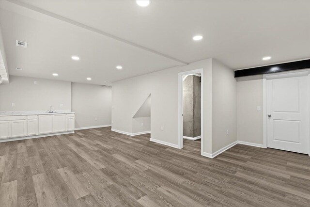 finished basement with baseboards, recessed lighting, visible vents, and light wood-style floors