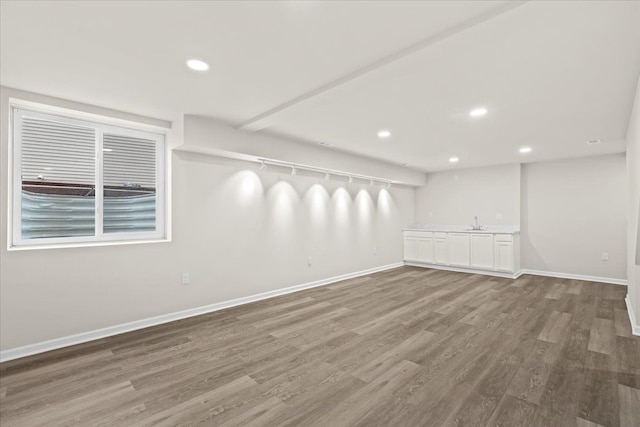 interior space with a sink, recessed lighting, wood finished floors, and baseboards