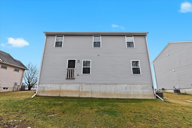 back of house with cooling unit and a lawn