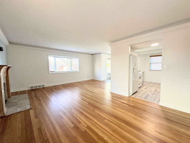 unfurnished living room with light wood-style floors, a wealth of natural light, visible vents, and a fireplace