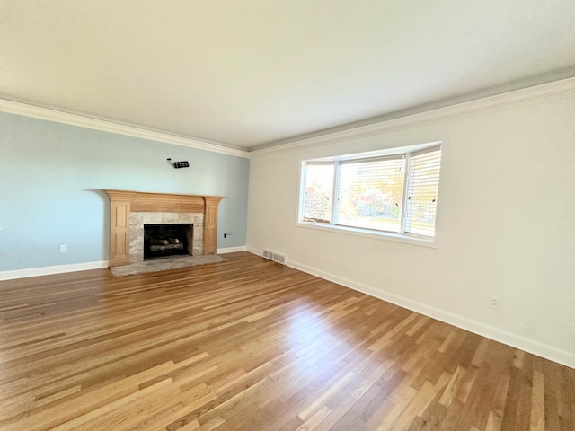 unfurnished living room with ornamental molding, visible vents, light wood-style flooring, and a tiled fireplace