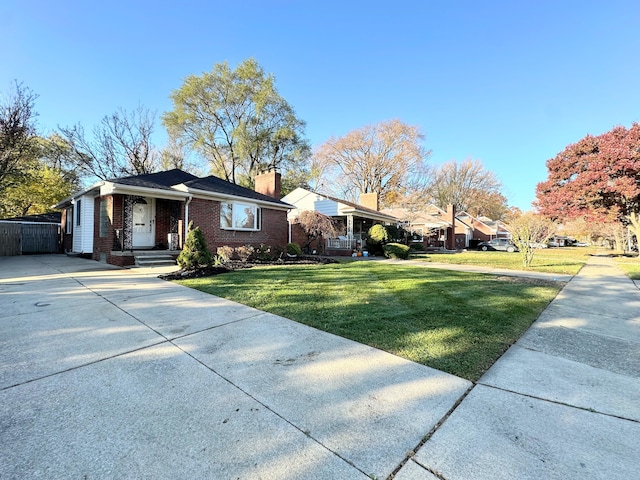 view of front of house featuring concrete driveway, brick siding, a chimney, and a front lawn