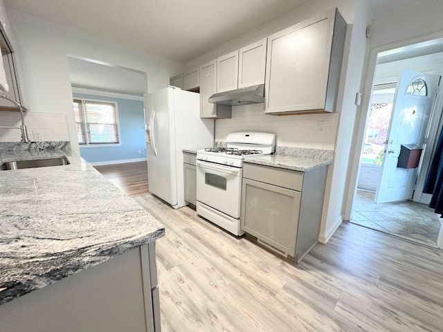 kitchen with under cabinet range hood, white appliances, a sink, gray cabinets, and decorative backsplash