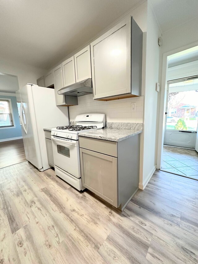 kitchen with a healthy amount of sunlight, white appliances, under cabinet range hood, and backsplash