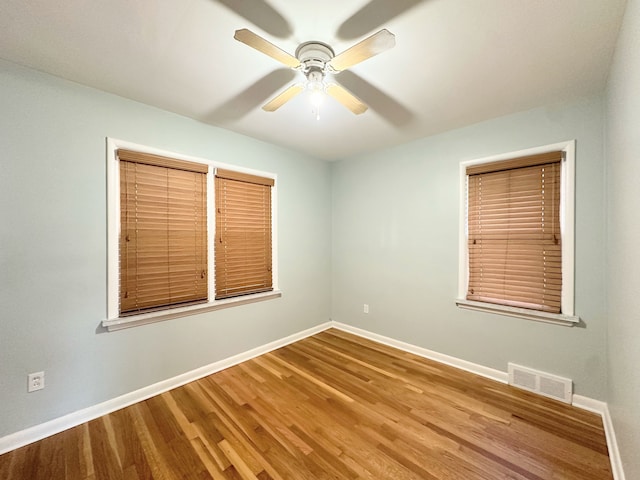 empty room with baseboards, visible vents, ceiling fan, and wood finished floors