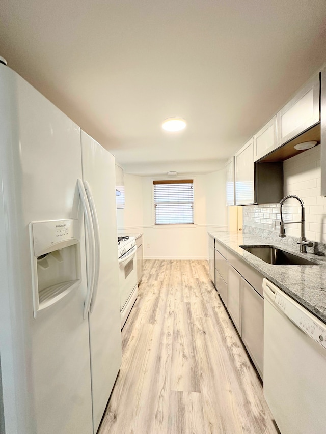 kitchen with light wood-style flooring, backsplash, white cabinets, a sink, and white appliances