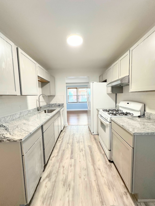 kitchen featuring backsplash, a sink, light wood-type flooring, white appliances, and under cabinet range hood