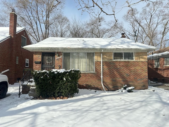 bungalow-style house with a chimney and brick siding