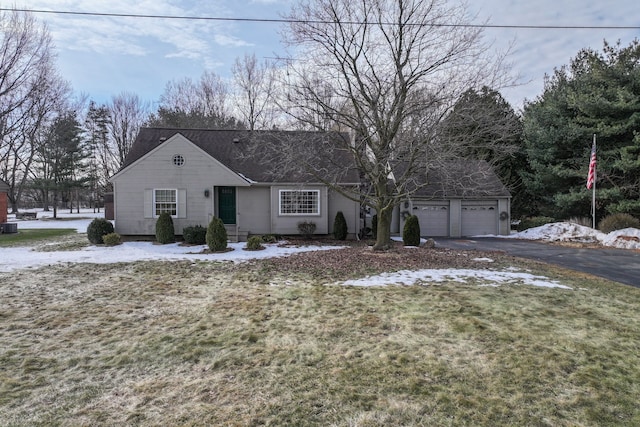 view of front of property featuring driveway, a lawn, an attached garage, and central air condition unit