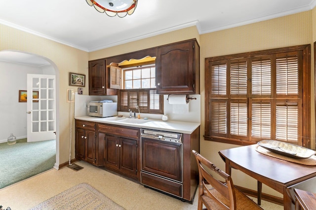 kitchen featuring arched walkways, white microwave, a sink, light countertops, and paneled dishwasher