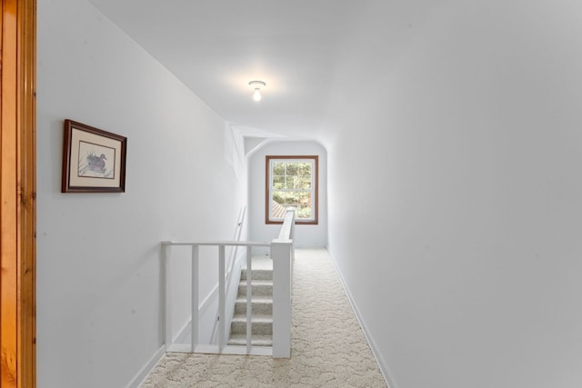 corridor featuring carpet, baseboards, and an upstairs landing