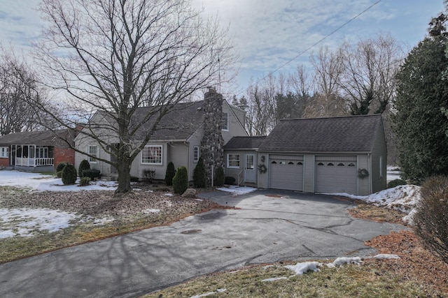 view of front of house featuring driveway, an attached garage, a chimney, and roof with shingles