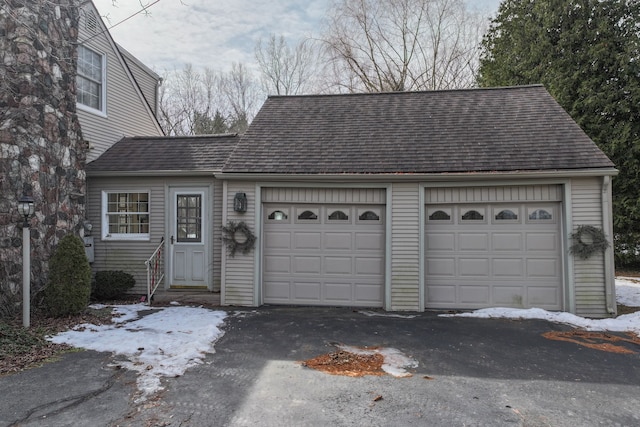 view of front facade with a garage, roof with shingles, and driveway