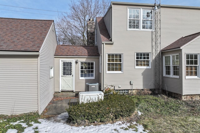 rear view of property with a chimney and central air condition unit