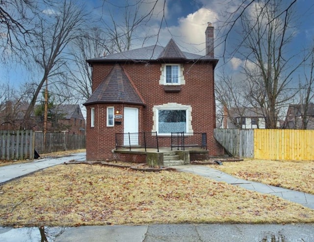 view of front of house featuring a front yard, a chimney, fence, and brick siding