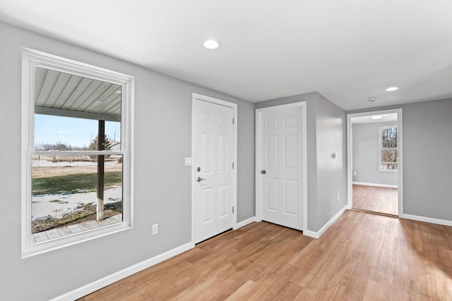 foyer featuring a wealth of natural light, light wood-style flooring, and baseboards