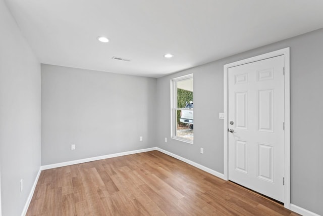 spare room with visible vents, baseboards, and wood finished floors