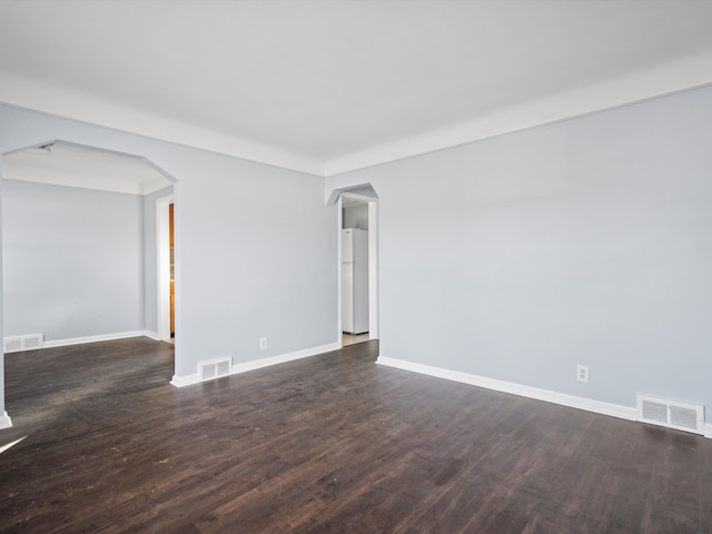 unfurnished room with arched walkways and visible vents