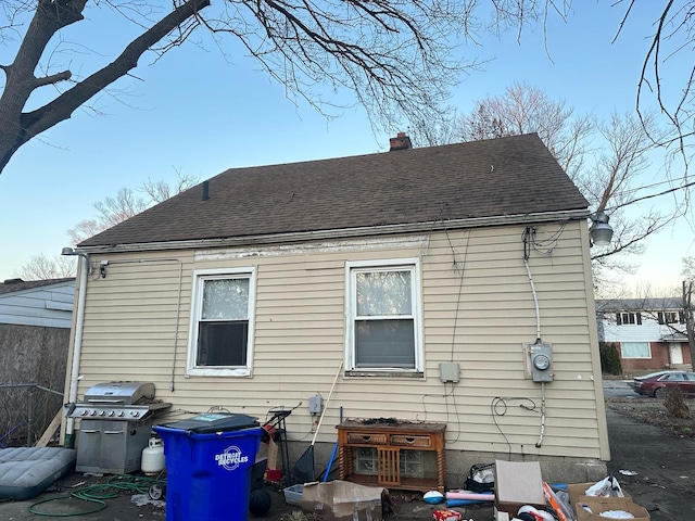 back of property with roof with shingles and a chimney