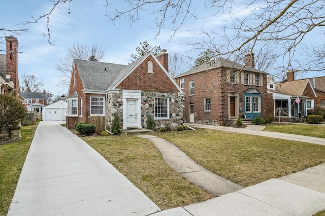 view of front facade featuring an outbuilding, brick siding, a shingled roof, a detached garage, and a front yard