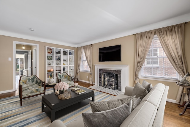 living room with baseboards, a tiled fireplace, and wood finished floors