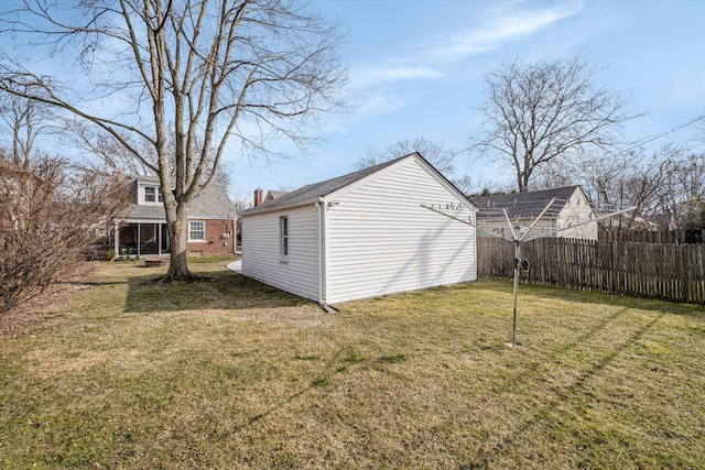 exterior space featuring fence, an outbuilding, and a yard