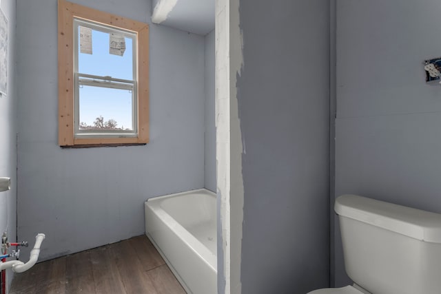 bathroom featuring toilet, a tub, and wood finished floors