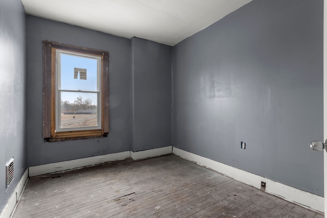 spare room featuring wood-type flooring and baseboards