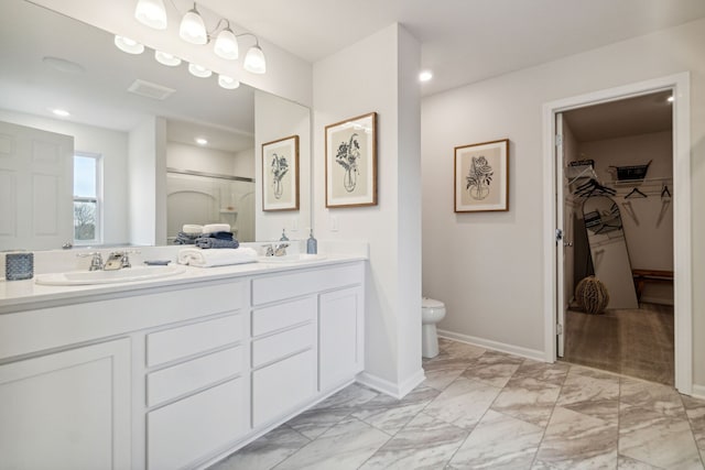 full bath with double vanity, marble finish floor, toilet, and a sink