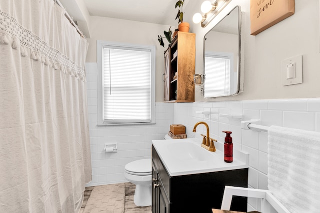 full bath with toilet, a wainscoted wall, tile walls, and vanity