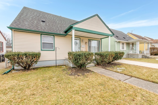 view of front of house with a porch, a front lawn, and roof with shingles