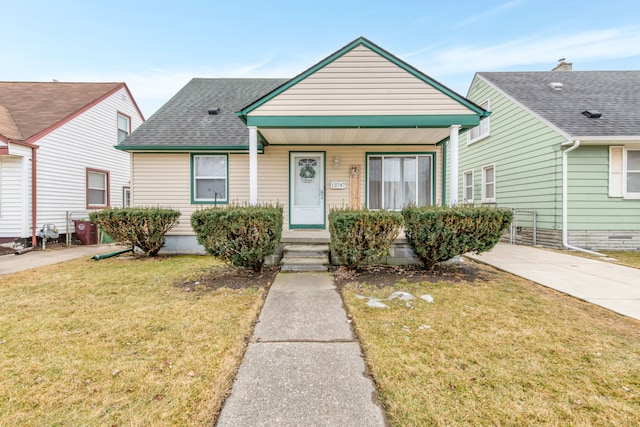 view of front of home featuring a shingled roof, a front yard, and a porch