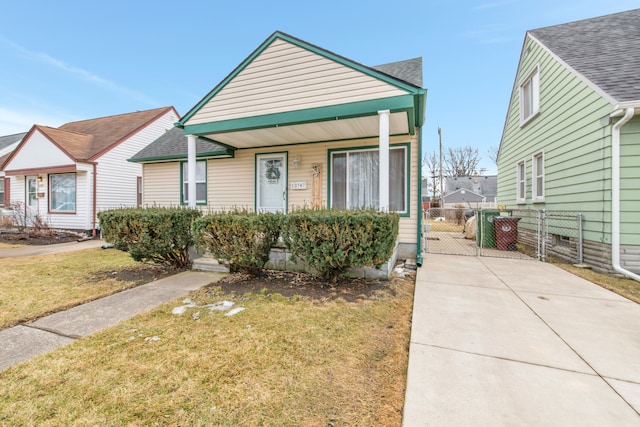 view of front of home featuring roof with shingles, a gate, fence, a front lawn, and a porch