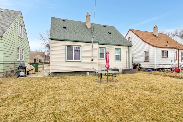 rear view of property with a chimney, fence, a lawn, and roof with shingles