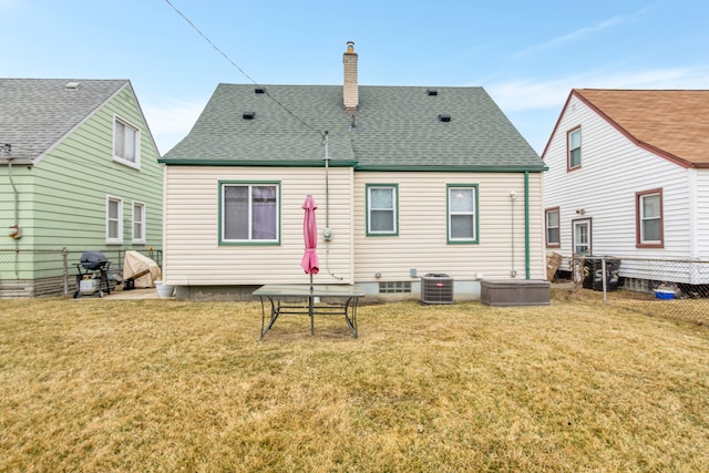 back of property with a chimney, fence, a lawn, and roof with shingles