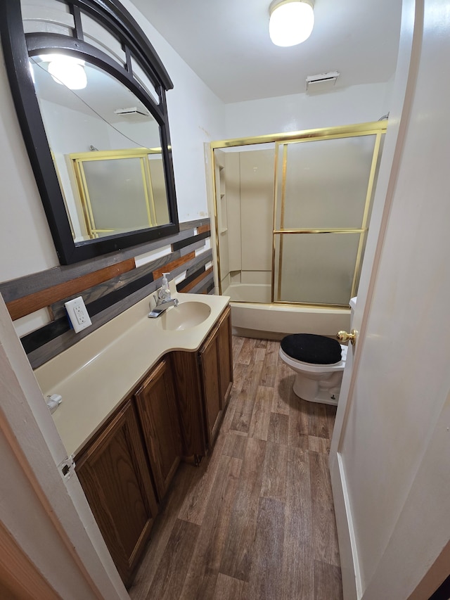 full bathroom featuring combined bath / shower with glass door, vanity, toilet, and wood finished floors