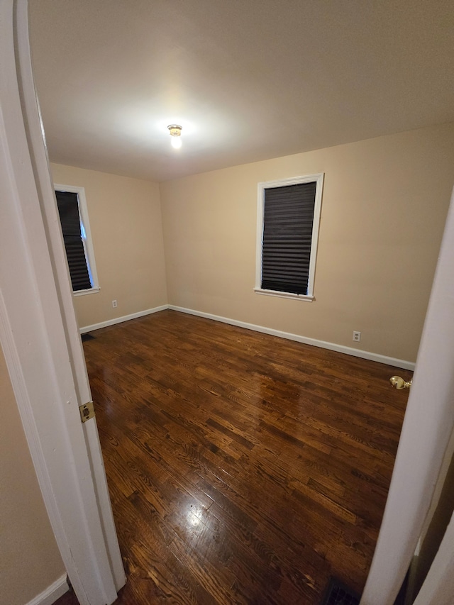 unfurnished room featuring baseboards and dark wood finished floors