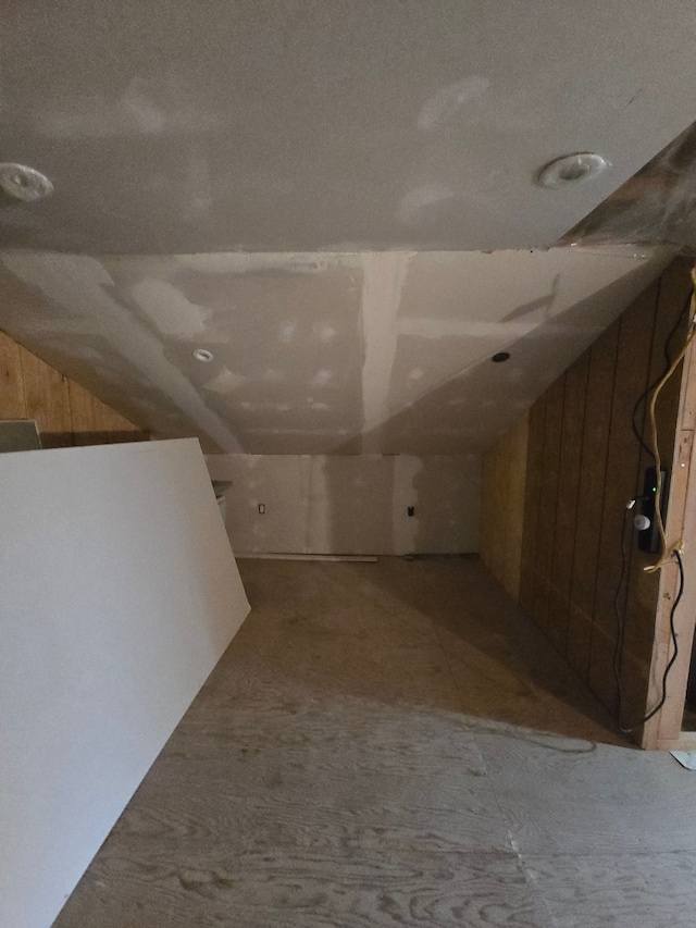 hall featuring lofted ceiling and wood walls