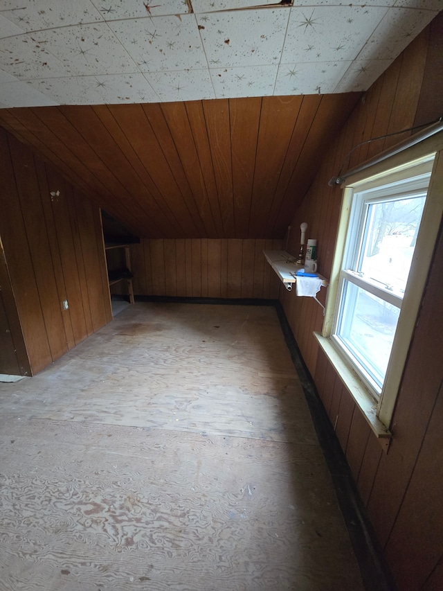 additional living space featuring lofted ceiling, light wood finished floors, wooden ceiling, and wooden walls