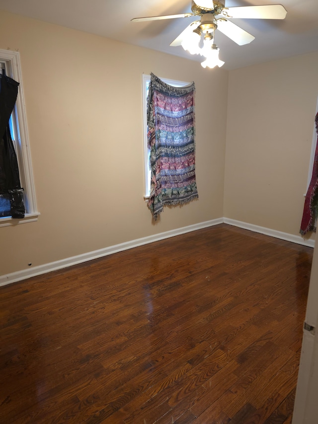 empty room with dark wood-type flooring, baseboards, and a ceiling fan