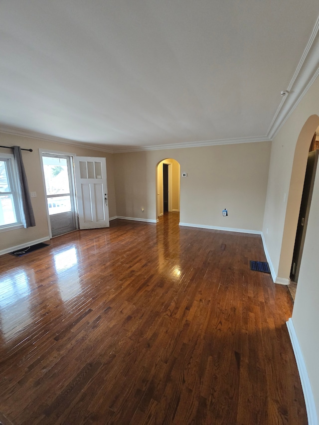 unfurnished living room featuring ornamental molding, arched walkways, dark wood-style flooring, and baseboards