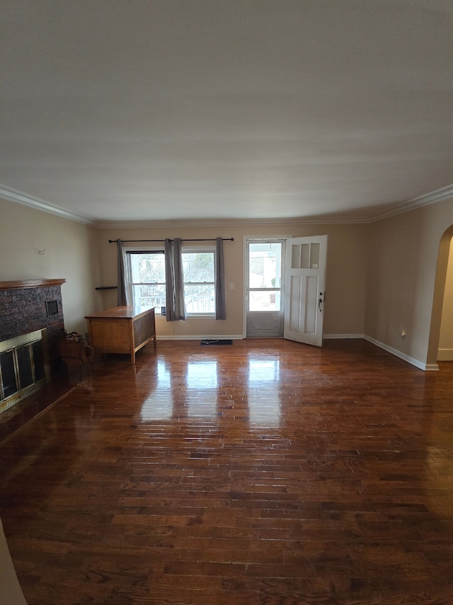 unfurnished living room with crown molding, dark wood finished floors, a wealth of natural light, and a glass covered fireplace